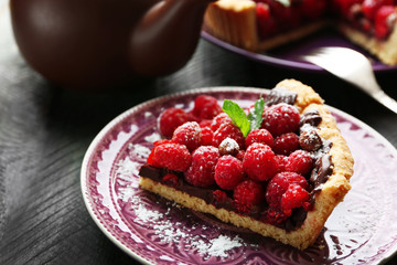 Piece of tart with fresh raspberries, on wooden background