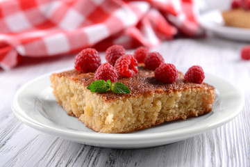 Fresh pie with raspberry in white plate on wooden table, closeup