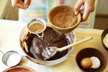 Woman preparing dough for chocolate pie on table close up