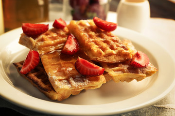 Sweet homemade waffles with strawberries  on plate, on table background