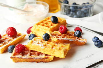 Sweet homemade waffles on tray, on light background