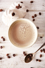 Cup of coffee with beans and zephyr on wooden table, top view