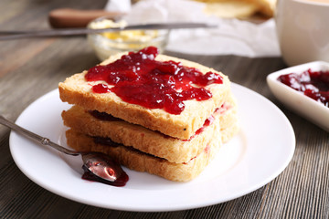 Bread with butter and homemade jam on wooden table, closeup