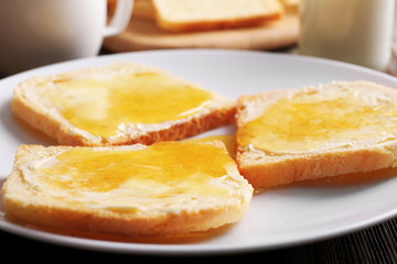 Bread with butter and homemade jam in white plate, closeup