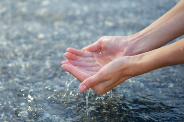Female hands touching sea water