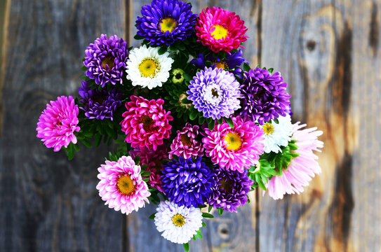 Bouquet of pink, violet and white aster over wooden background,