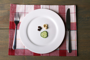 fork and knife beside the plate of food on a napkin on wooden table