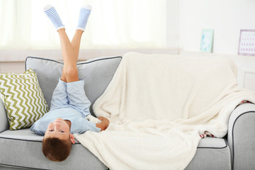Obraz na płótnie Canvas Little boy sitting on sofa, on home interior background