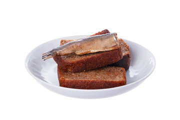 Fried slices of black bread and fish cooked sprats in oil on a white plate.