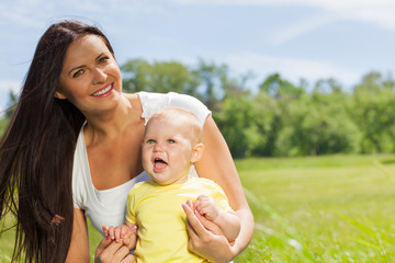 Fototapeta premium Happy mother with child in the green meadow