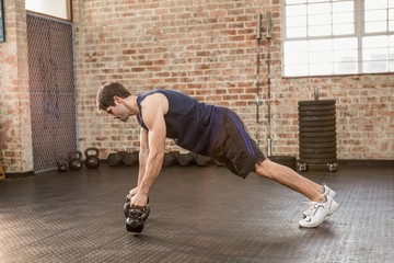 Man doing push up holding kettlebell