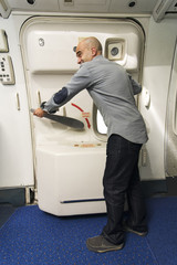 caucasian man passenger  trying to open the emergency exit  door in plane