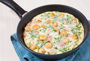 omelet with mushrooms, ham and cheese in a frying pan