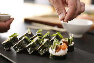 Sushi master przyrządza futomaki. Klasyczne  grube rolki futomaki podane na kamiennym talerzu - obrazy, fototapety, plakaty