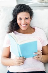 Pregnant woman reading book while lying