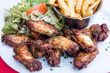 Chicken wings with sauce and golden French fries potatoes