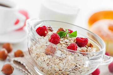 Delicious healthy food breakfast. Oatmeal  muesli with raspberry and hazelnut on table.