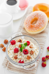 Breakfast with oatmeal, coffee and doughnuts. Muesli with fruits and nuts. Top view.
