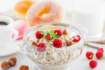 Healthy breakfast, oatmeal muesli on table with coffee and doughnuts.