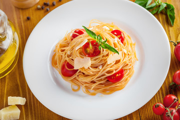 Italian pasta, spaghetti with tomato, parmesan and basil, top view, close-up.