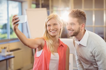 Businesswoman taking selfie with male colleague