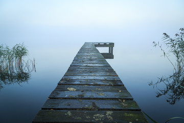 Close up of old, wooden jetty in the autumn fog. © sanderstock