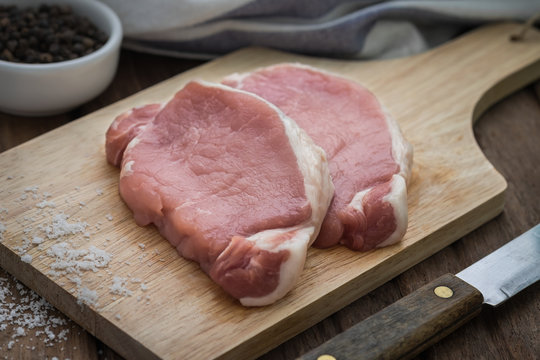 Raw pork meat sliced on wooden cutting board
