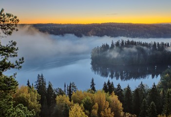Fototapeta premium Autumn landscape in the morning. Thick fog above a lake at Aulanko nature reserve park in Finland. 