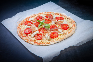 Home made raw pizza with prosciutto and blue cheese. The dough w