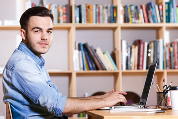 Obraz premium Side view of a handsome man working on laptop