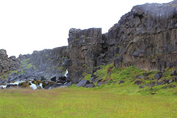 Blick auf Felsformationen und einen Wasserfall im Nationalpark Thingvellir (Island)