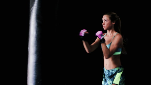 Beautiful Young Female Athlete Exercising for Self Defense with Boxing Gloves and Body Bag. Athletic Woman Fitness Training in Gym. Instagram Filter.