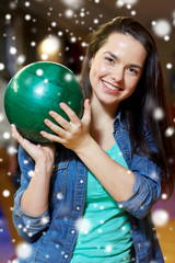 Fototapeta na wymiar happy young woman holding ball in bowling club