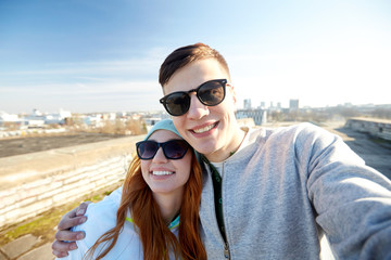 happy teenage couple taking selfie on city street