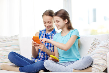 happy girls with smartphones sitting on sofa