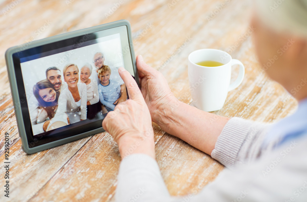 Poster senior woman with family photo on tablet pc screen