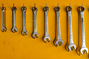 Metal wrenches hanging on a yellow board wall