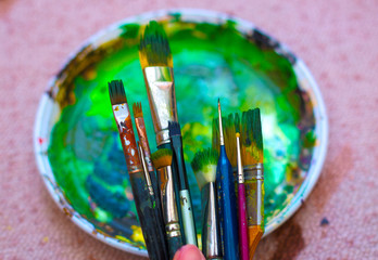 Fototapeta premium Paint brushes in man hand to the painting palette with colors 
