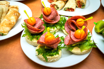 canape with salami, lettuce and cape gooseberry on the table