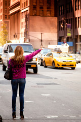 Young woman waving for yellow cab