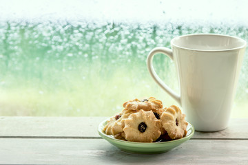 Cookie and coffee cup on rainy day window background 
