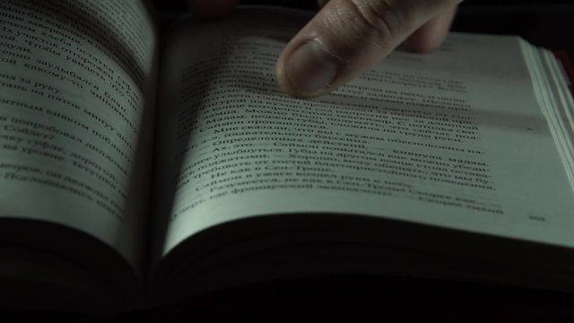 The hand is flipping the page of the book