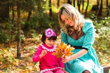 happy mother with her daughter for a walk in autumn park