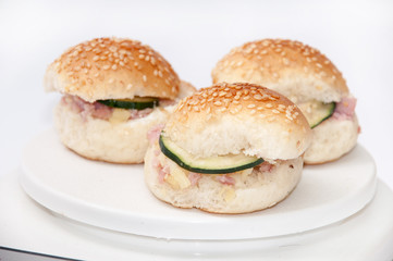 Small burger sandwiches with ham and cucumber