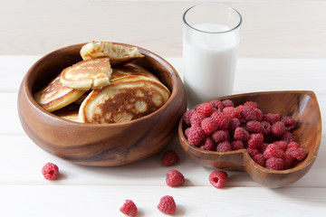 Fritters with a raspberry on wooden plate