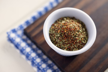 Pizza seasoning. High angle view of white bowl full of condiment mix for pizza. Very shallow depth of field.