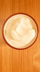 Plain yoghurt in a terracotta bowl on oak table