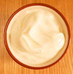 Plain yoghurt in a terracotta bowl on oak surface, square