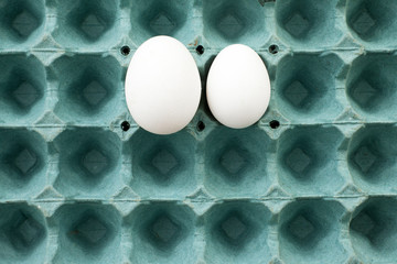 Different size. White Eggs. Top view of egg carton with two white eggs of different sizes in it. Comparison. 