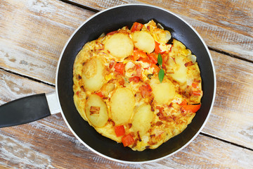 Omelette with potatoes, onions, red pepper and sweetcorn in frying pan
